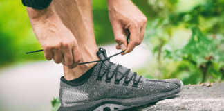 An aging worker tying his running shoe.